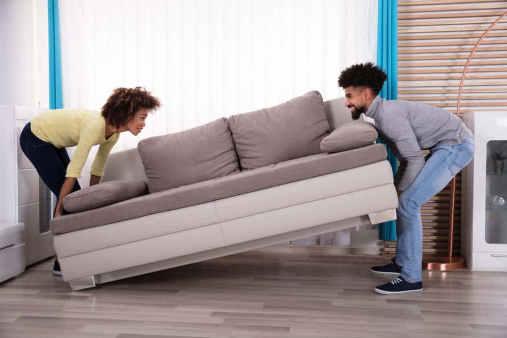 A young couple is lifting a sofa.