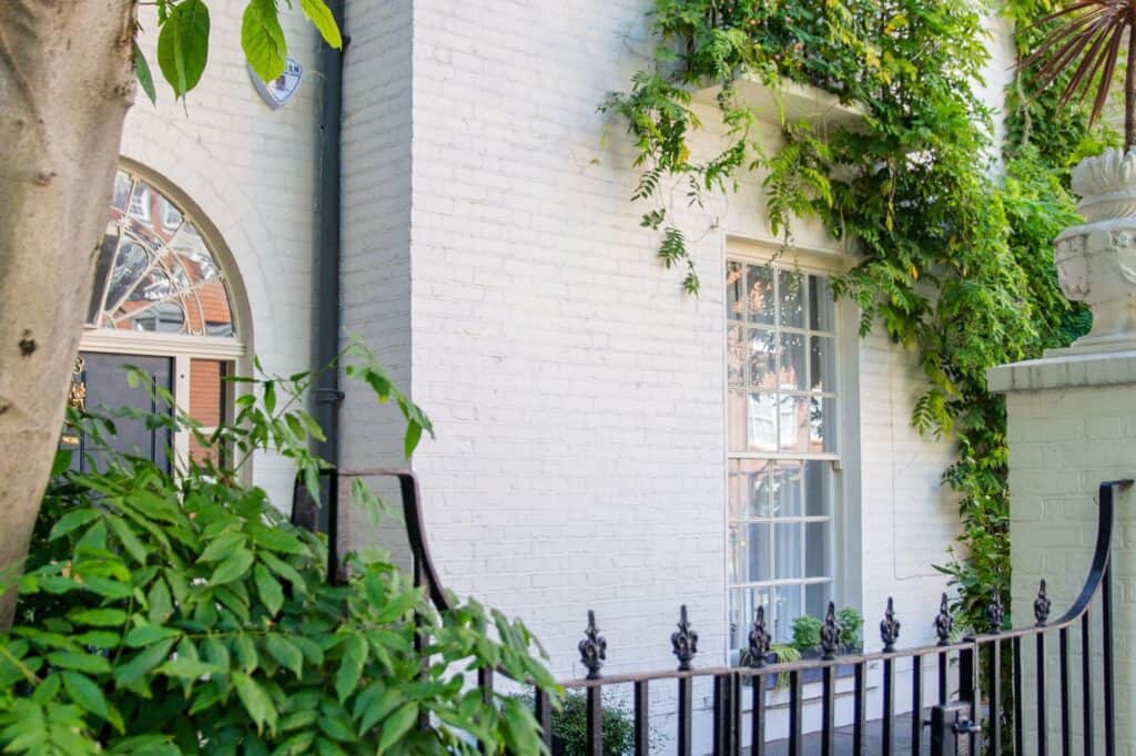 A white brick house with a fence and a balcony