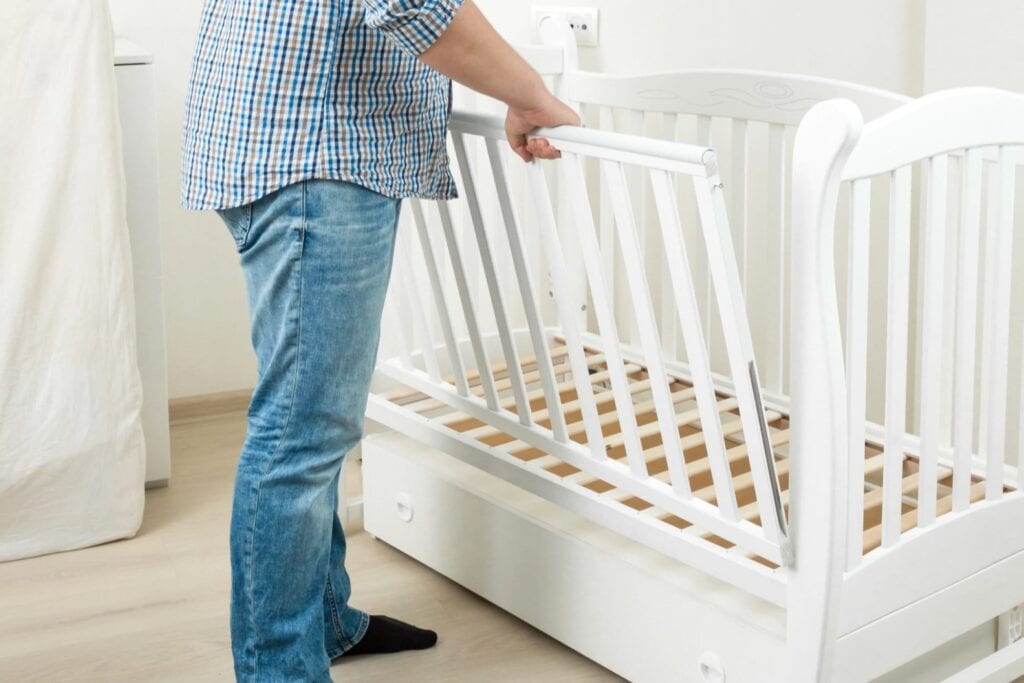 A father is disassembling his baby's cot.