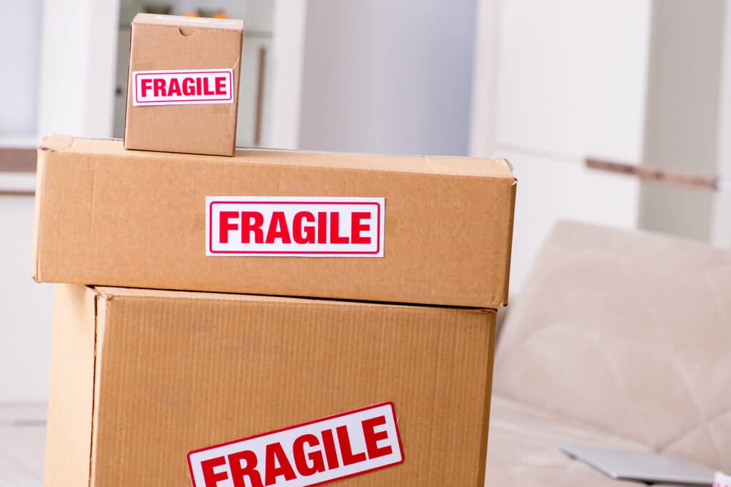 Stacked cardboard boxes with red and white "FRAGILE" labels prominently displayed on each box.