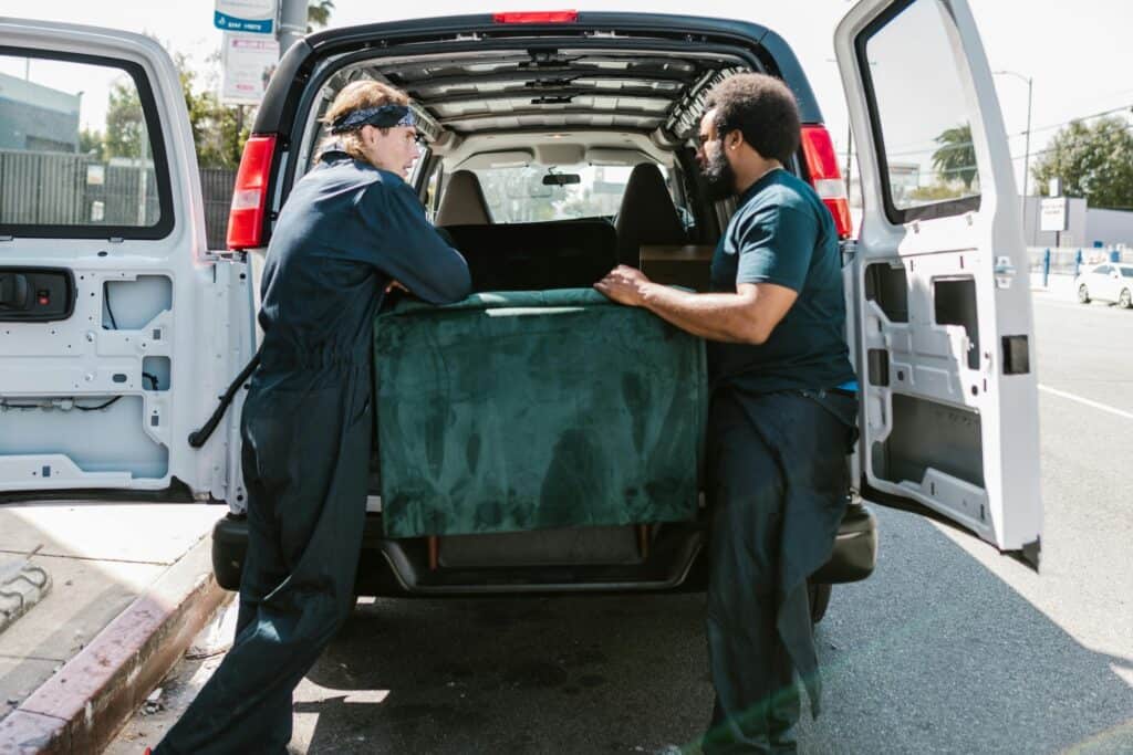 Two professional movers are placing a furniture at the back of the van in the concept of a Man and Van in Battersea.