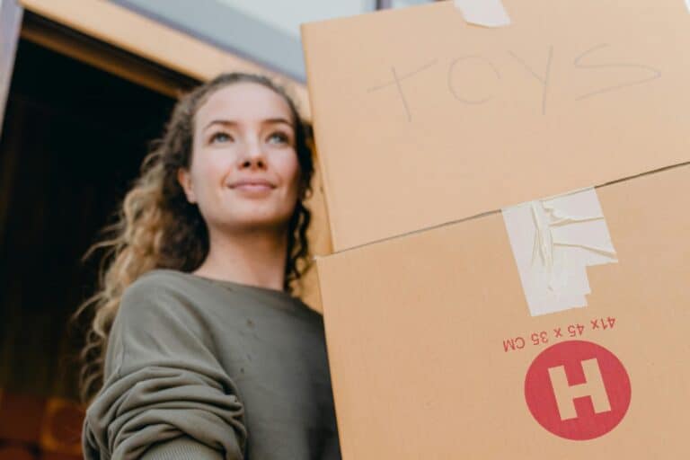 A woman is carrying boxes in the concept of 'how to save money when moving to Battersea'.