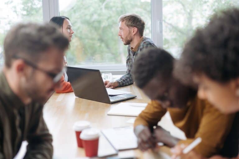 Busy employees in a meeting room in the concept of 'How to Minimise Disruption During an Office Move'.